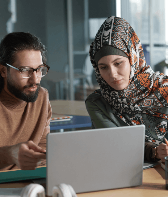 Two reviewers compare Arabic dialect phrasing on printed pages, illustrating Arabic Translation Services in Houston.