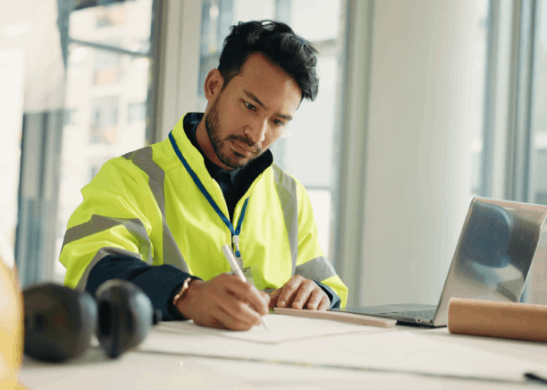 An engineer checks a bilingual safety diagram and manual pages, using Spanish Translation Services in Houston for academic.